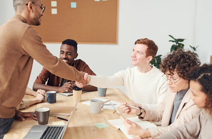 Team members shaking hands across a table